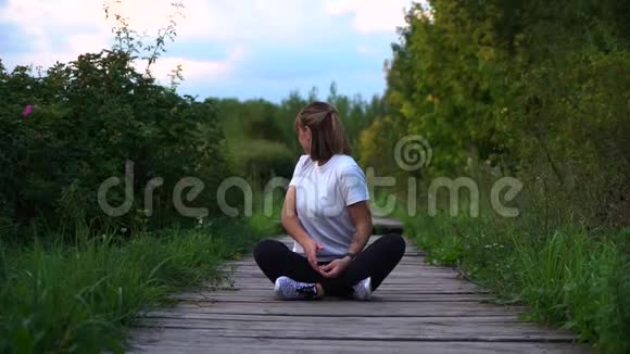 穿着白色t恤的女孩坐在木桥上转身视频的预览图