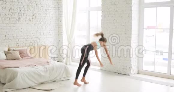 灵活的年轻女性在家做近墙倒立练习瑜伽视频的预览图