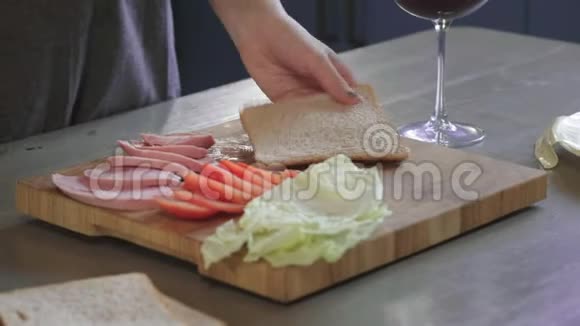 女人在厨房的木板上用刀把俱乐部三明治切成两半在家里做快餐厨师是视频的预览图