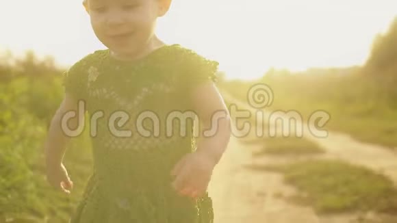 在阳光明媚的夏日傍晚微笑的女婴沿着乡间小路奔跑视频的预览图