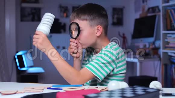 一个男孩通过放大镜检查灯泡视频的预览图