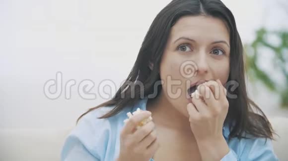 慢点在电影情节中一个被卷入其中的女人正在咀嚼爆米花她的手里全是玉米复制空间4K视频的预览图