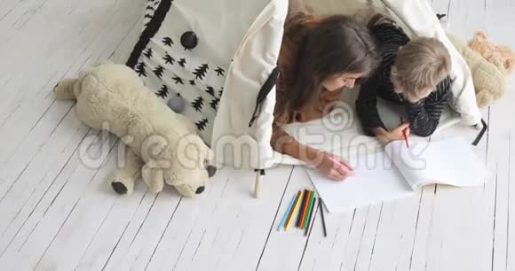 家庭的母亲和儿子一起画铅笔躺在托儿所顶部的视图视频的预览图