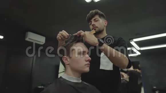 理发师用剪刀剪客户的头发有魅力的男性正在理发店理发手持视频的预览图