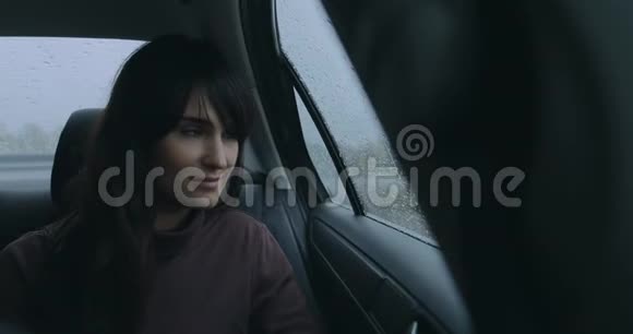一个女人在雨天坐在车里看窗户视频的预览图