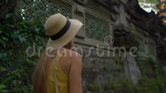 一位穿着黄色连衣裙的年轻女子在坎布汉岭散步或画家乌布的人行道上散步旅行目的地视频的预览图