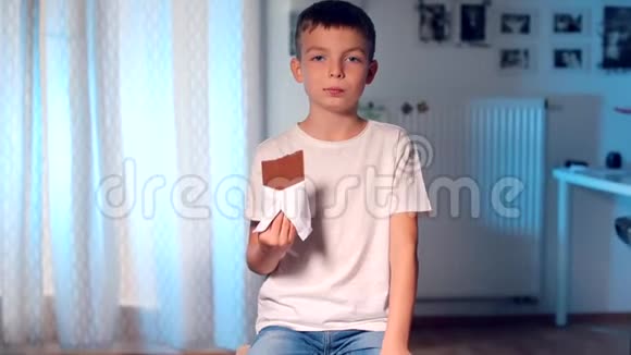 冷静的男孩坐在高椅子上男孩吃巧克力棒视频的预览图