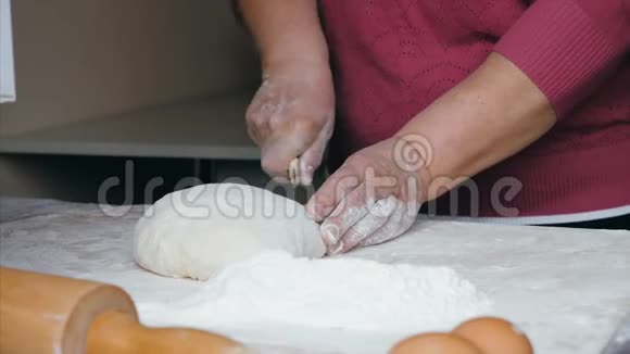 高级女性的特写双手是在家庭厨房把面团切成碎片视频的预览图