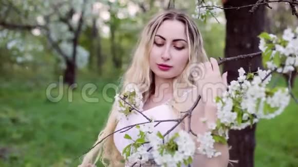年轻女子站在一棵开花的树旁视频的预览图