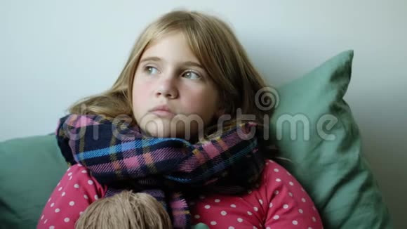 生病的感冒小女孩正坐在毯子下面带着围巾喝热凉茶有爱心的母亲视频的预览图