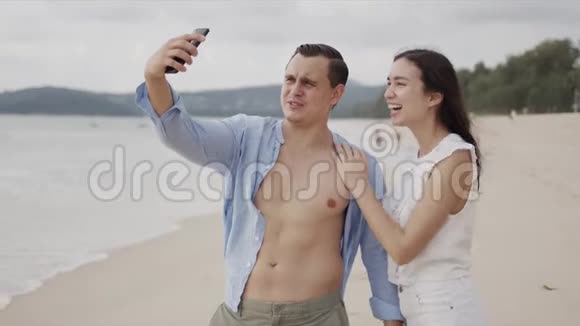 喜欢在智能手机上自拍在异国情调的海洋边微笑的人们感到高兴视频的预览图