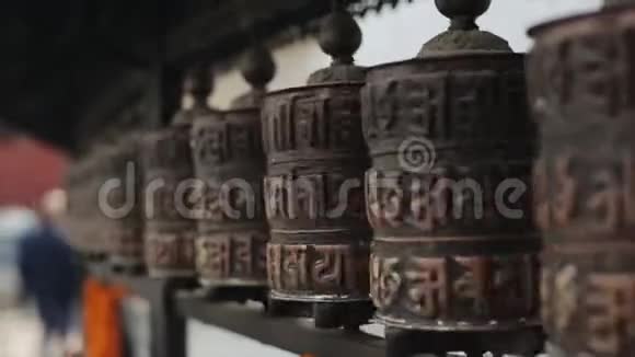 在尼泊尔加德满都的一排轮子上旋转佛教祈祷轮的近景神庙视频的预览图