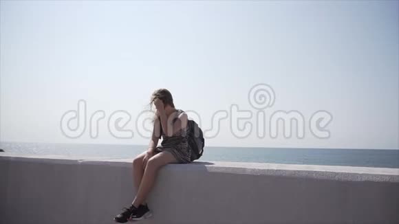 一个带背包和耳机的女孩坐在长廊上慢动作视频的预览图