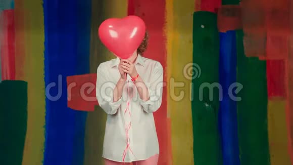 情人节美女女孩带着红色的气球笑着彩色彩虹的背景玩得开心快乐的模特视频的预览图