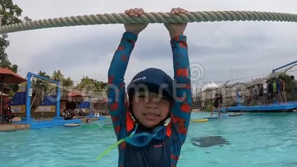 在水上乐园的水上游乐场里吊在绳子上的男孩视频的预览图