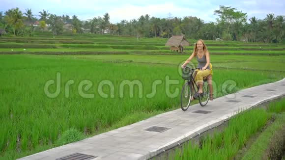 一个年轻的女人和她的小儿子骑着自行车穿过美丽的稻田前往东南亚构想视频的预览图