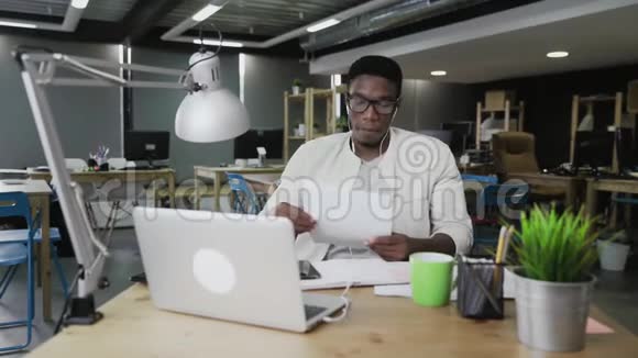 带着耳机的非洲男人在现代办公室举行视频会议视频的预览图
