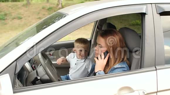 淘气的孩子在车里干扰妈妈他用手闭上她的眼睛视频的预览图