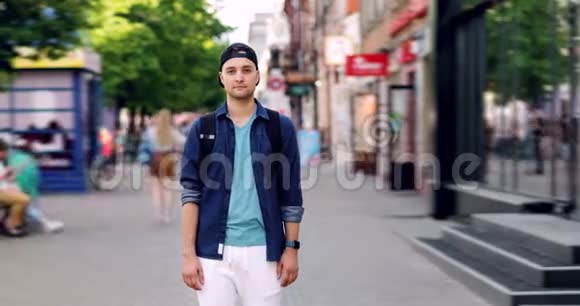 男子嬉皮士站在户外的城市街道上严肃的脸视频的预览图