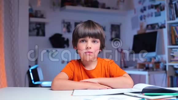 男孩坐在学校的一张桌子旁把手举到最上面视频的预览图