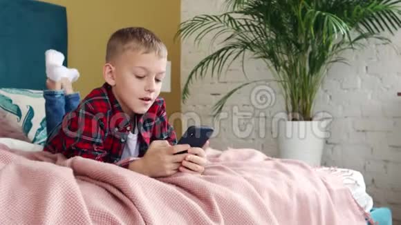 一个八岁的小男孩用智能手机躺在床上视频的预览图