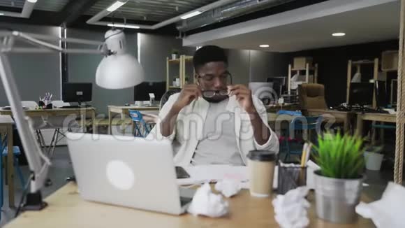 头疼疲惫的非洲男人在用手提电脑视频的预览图