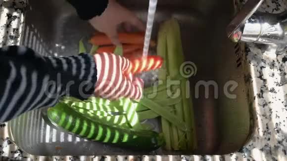 白种人用其他蔬菜在银堆上的水龙头下洗胡萝卜视频的预览图