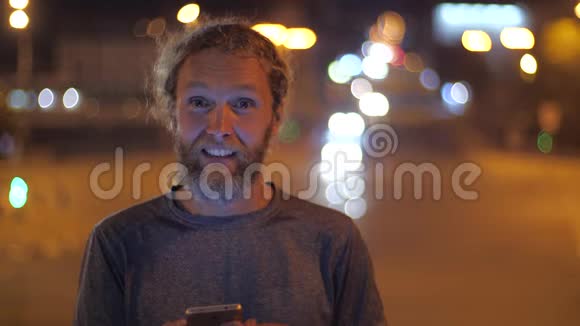 一位英俊的白种人留着长胡子的年轻男子的特写肖像他带着智能手机通过手势和视频的预览图