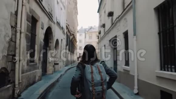 镜头跟随美丽的女人背包和相机沿着秋天的巴黎街道摆姿势微笑缓慢的运动视频的预览图