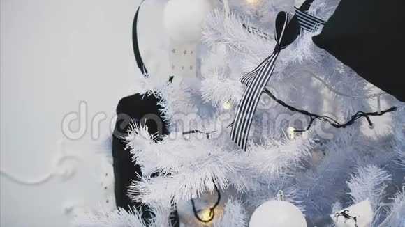 把条纹蝴蝶结放在圣诞树树枝上的孩子的手视频的预览图