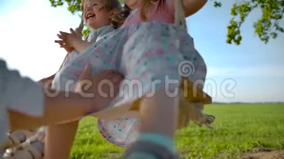 穿着白色连衣裙的快乐女人在秋千上摆动她的女儿视频的预览图