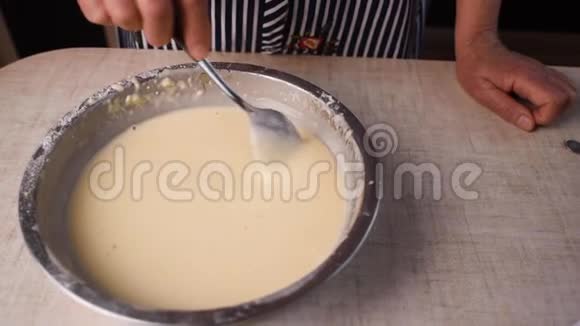 制作和搅拌面团的过程中女人手将液体面团与搅拌器混合在碗中视频的预览图