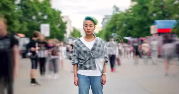 严肃的亚洲女士潮人站在街上的时间流逝视频的预览图