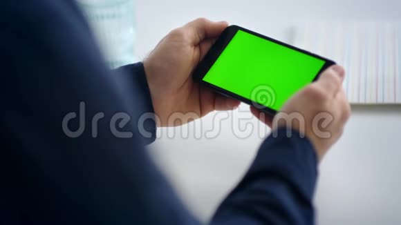 用绿色屏幕关闭手握智能手机男性手机视频的预览图
