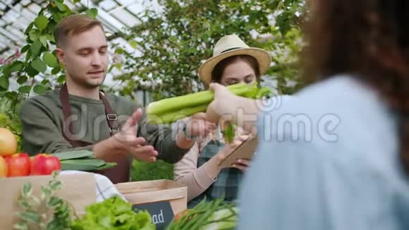 在农场市场买有机食品的女人把蔬菜送给售货员视频的预览图