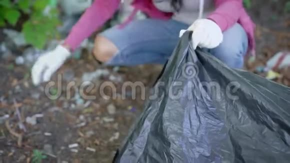女人正把垃圾放进袋子里夏天从林地里拿出来手上的特写镜头视频的预览图