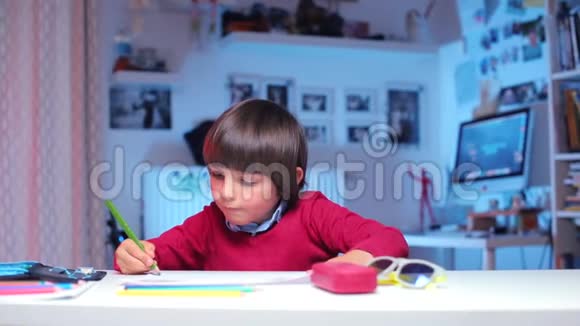 坐在桌子旁的孩子用铅笔画画看着相机视频的预览图
