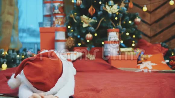 有趣的视频小孩子躺在冷杉下的红色毯子上做着滑稽的表情看起来像可爱的侏儒视频的预览图