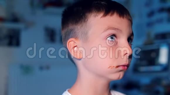 在蓝色背景下嚼巧克力的男孩视频的预览图