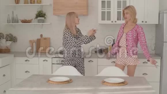 两个漂亮的金发白种人女孩在厨房跳舞女孩们在家里参加睡衣派对视频的预览图
