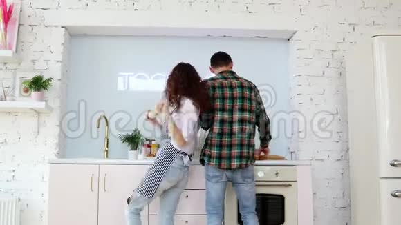 年轻快乐的夫妇在厨房做饭时跳舞视频的预览图