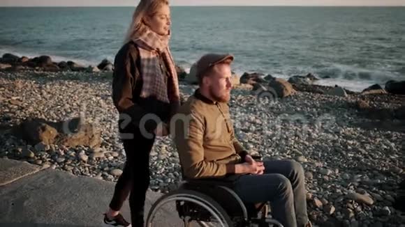 妻子正在海景的堤岸上载着残疾丈夫视频的预览图