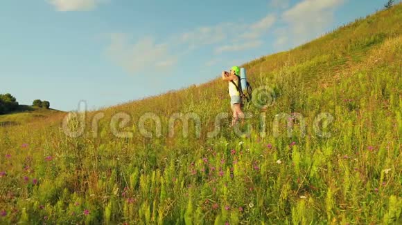 女徒步旅行者在山上背着一个背包和望远镜在电话中拍摄大自然视频的预览图