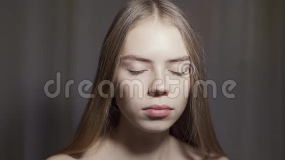 年轻女子在白色背景上睁开眼睛一个微笑的女孩在摄影棚里看着摄像机视频的预览图