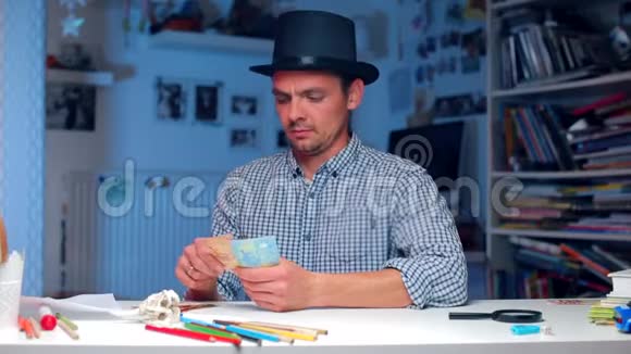 戴帽子的人在桌上数钱找到一张钞票拿走视频的预览图