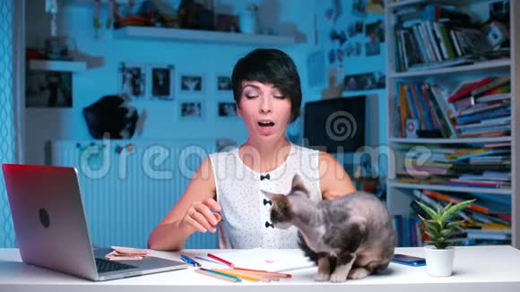坐在桌子旁过敏的女孩从猫的皮毛上打喷嚏视频的预览图