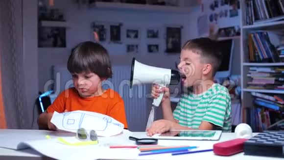 一个男孩通过扩音器向另一个男孩喊叫坐在桌子旁视频的预览图