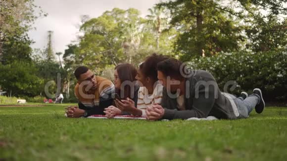 一群多种族的年轻朋友躺在草地上在公园里享受和度过时光视频的预览图