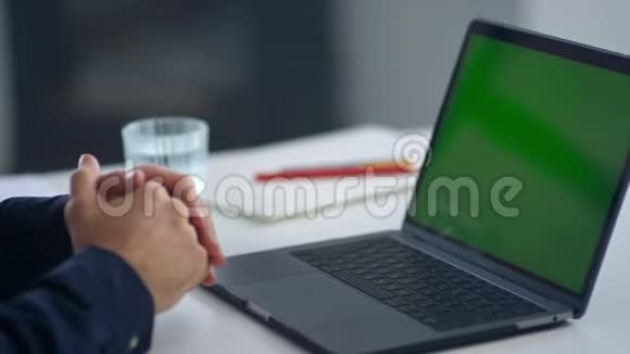 商人看着绿色屏幕笔记本电脑视频通话后男人挥手视频的预览图