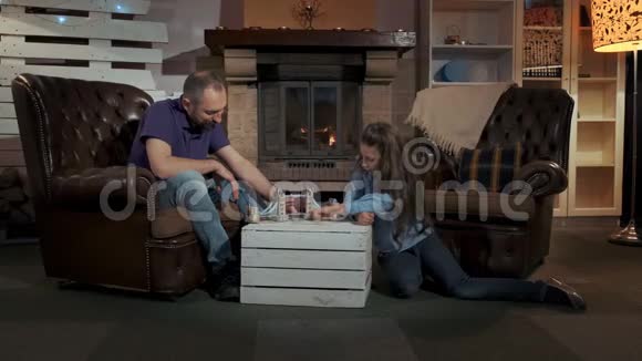 小女儿和爸爸一起在壁炉附近一间舒适的大客厅里玩耍视频的预览图
